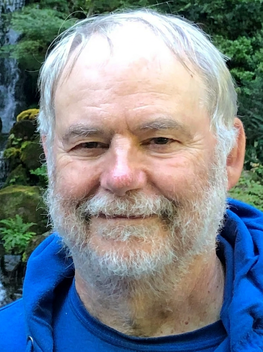 Portrait of Doug Chapman, photographed outdoors near a small waterfall